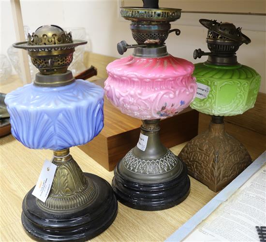 Three Edwardian oil lamps with coloured glass reservoirs